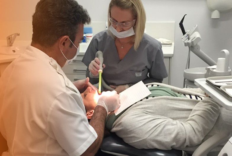 Dentist and assistant examining patient's teeth in a clinic.