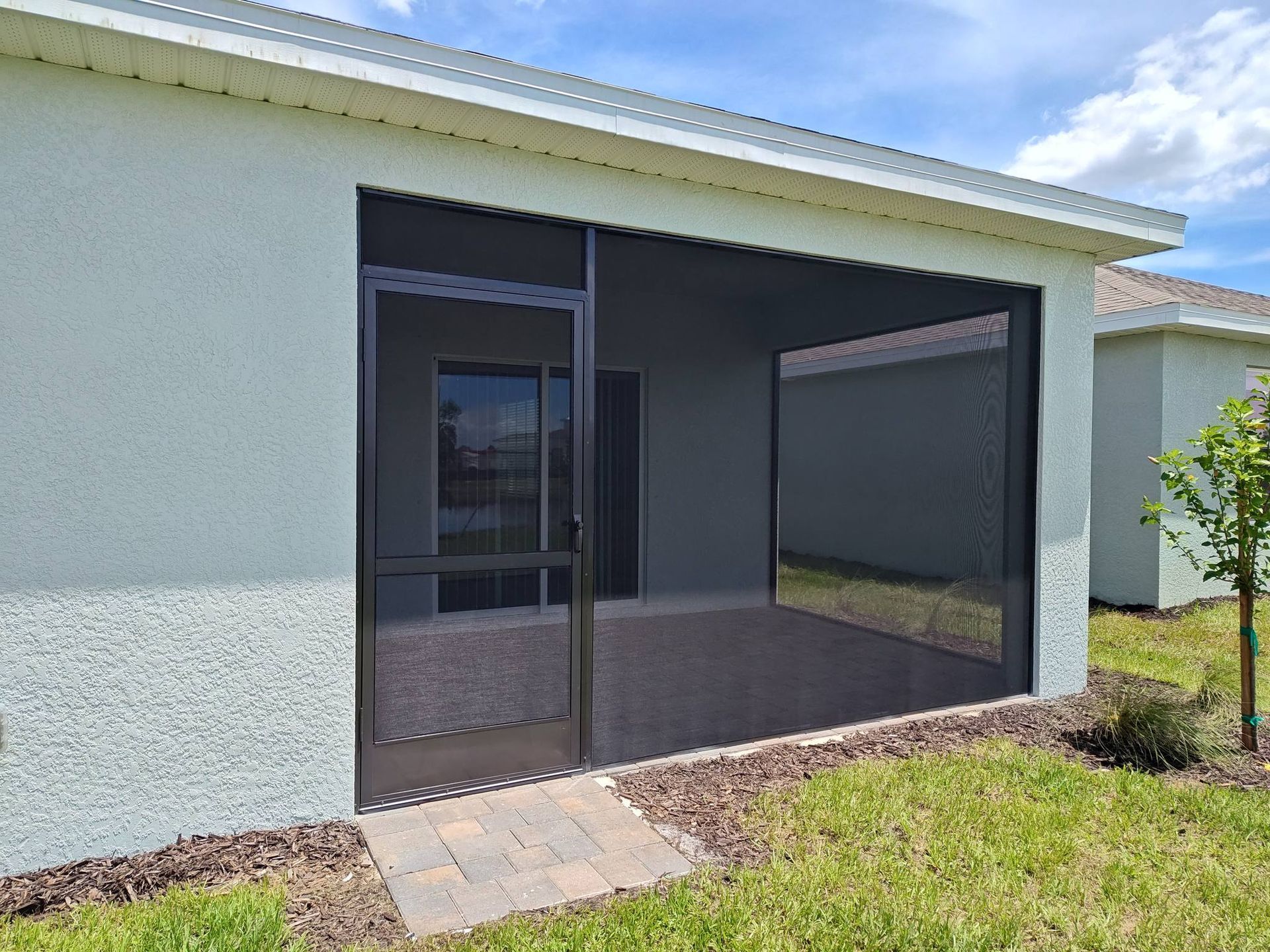 A house with a screened in porch and sliding glass doors.