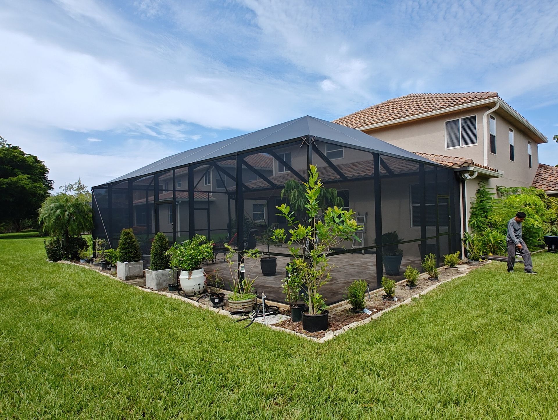 A man is standing in front of a house with a screened in porch.
