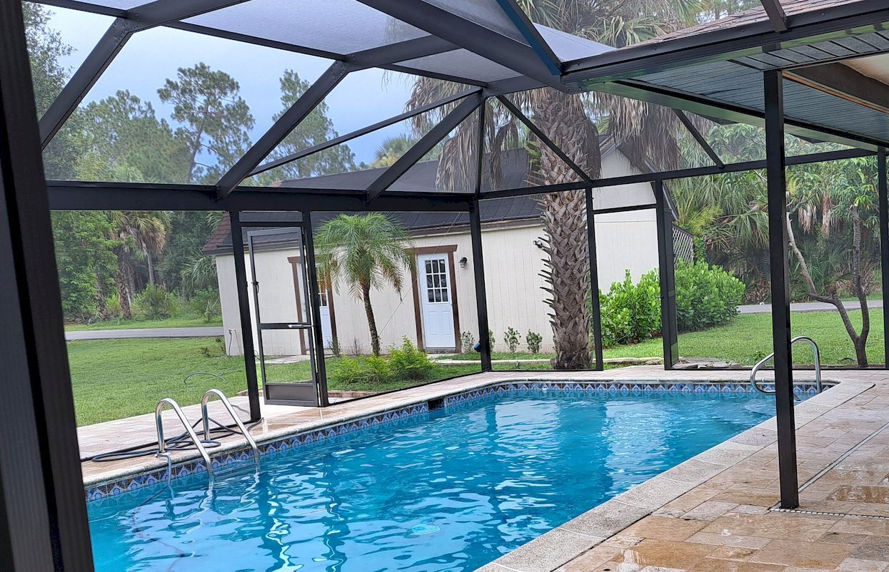 A large swimming pool is covered by a screened in area.