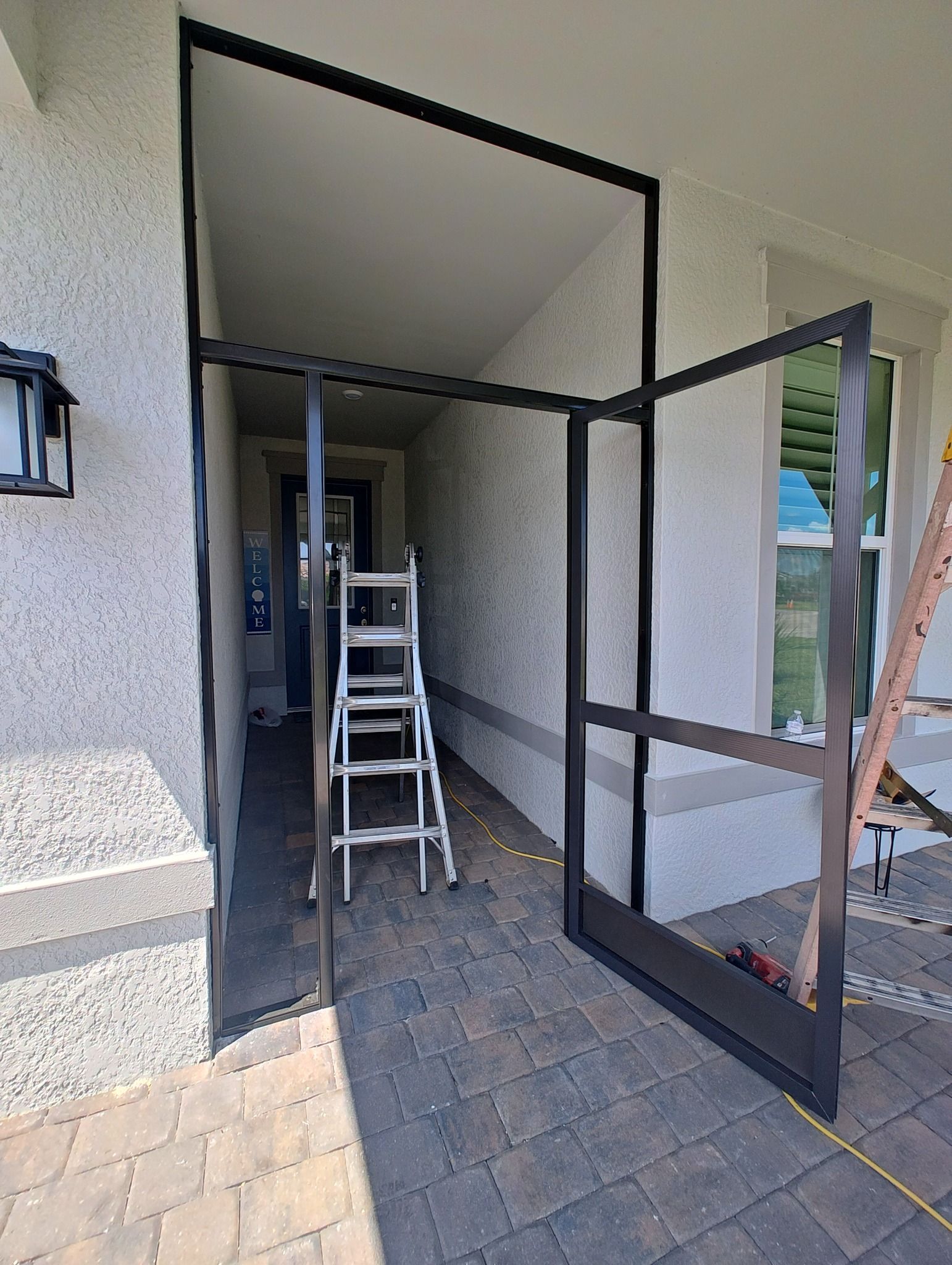 A screen door is being installed on the side of a house.
