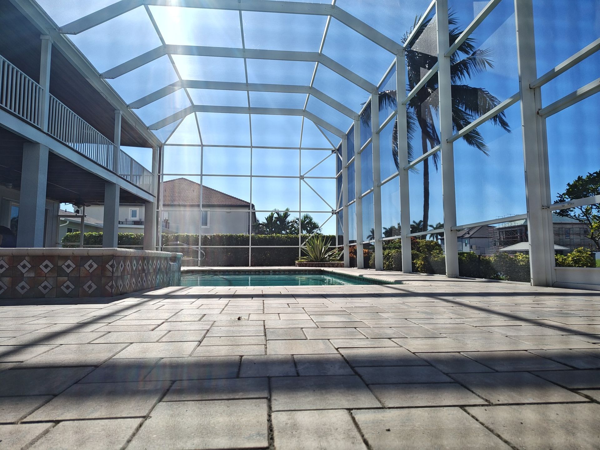 A large screened in swimming pool with palm trees in the background