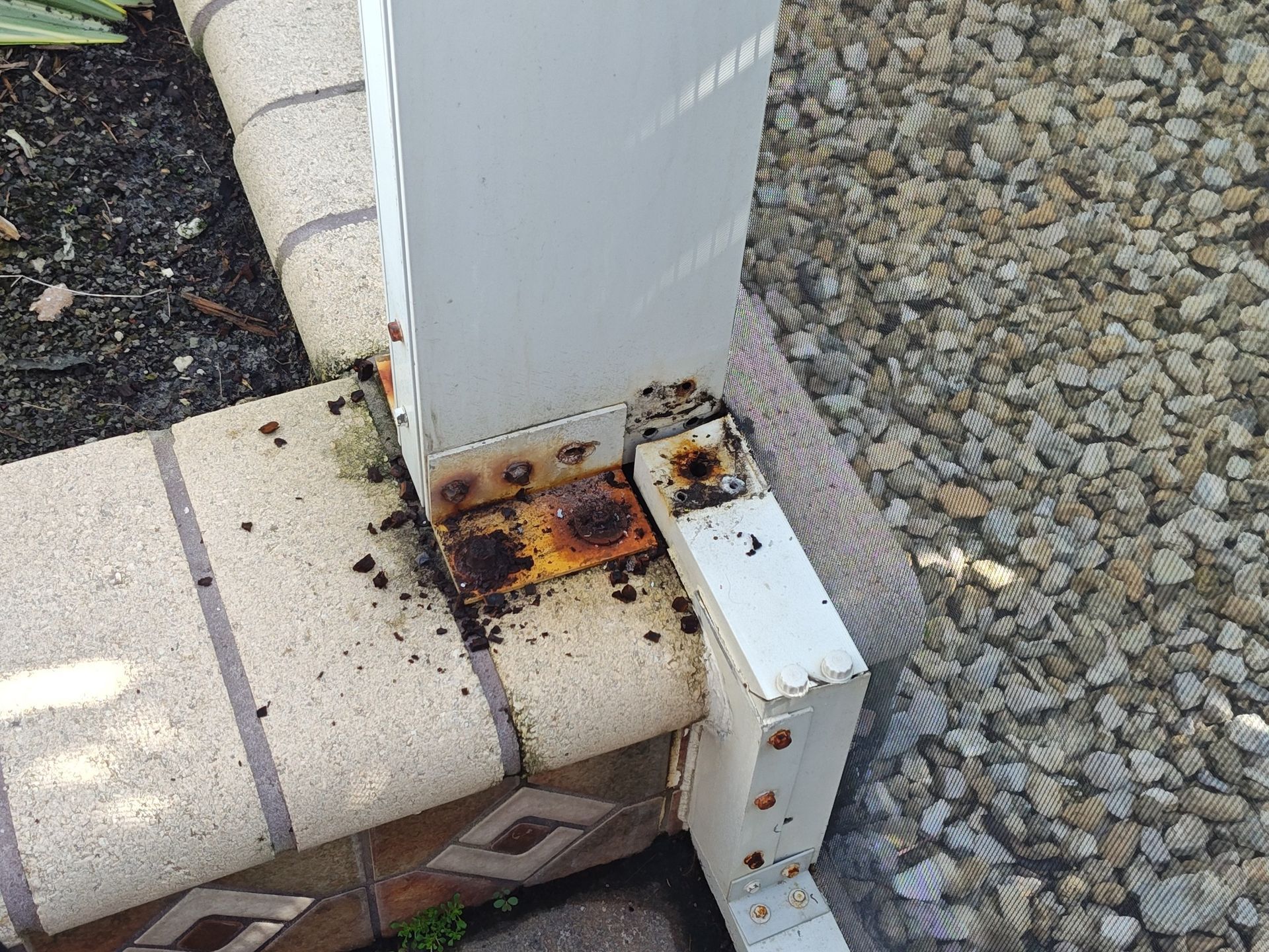 A rusty metal post is sitting on top of a brick wall.