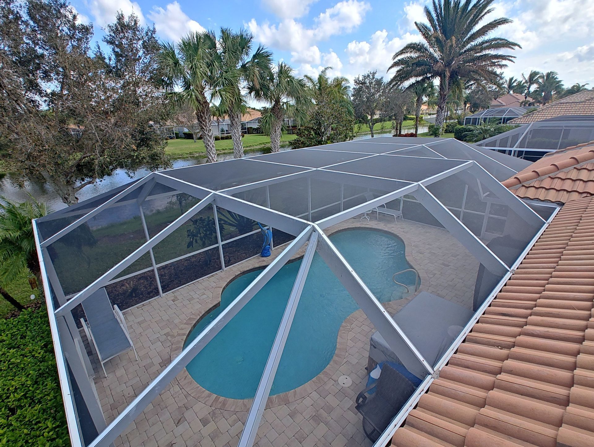 An aerial view of a swimming pool with a screened in area