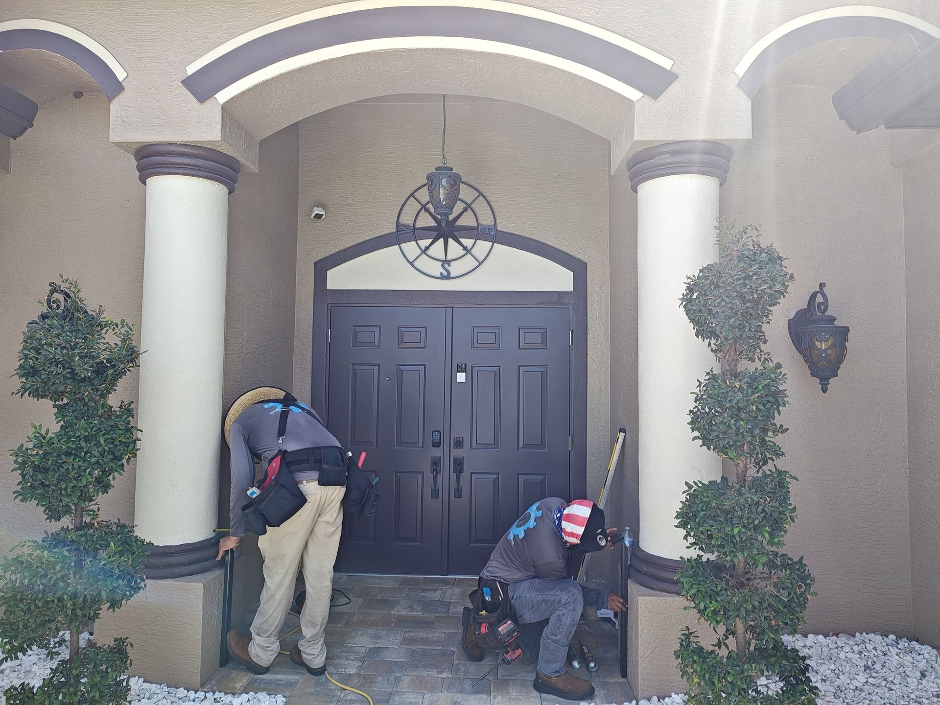 Two men are working on the front door of a house