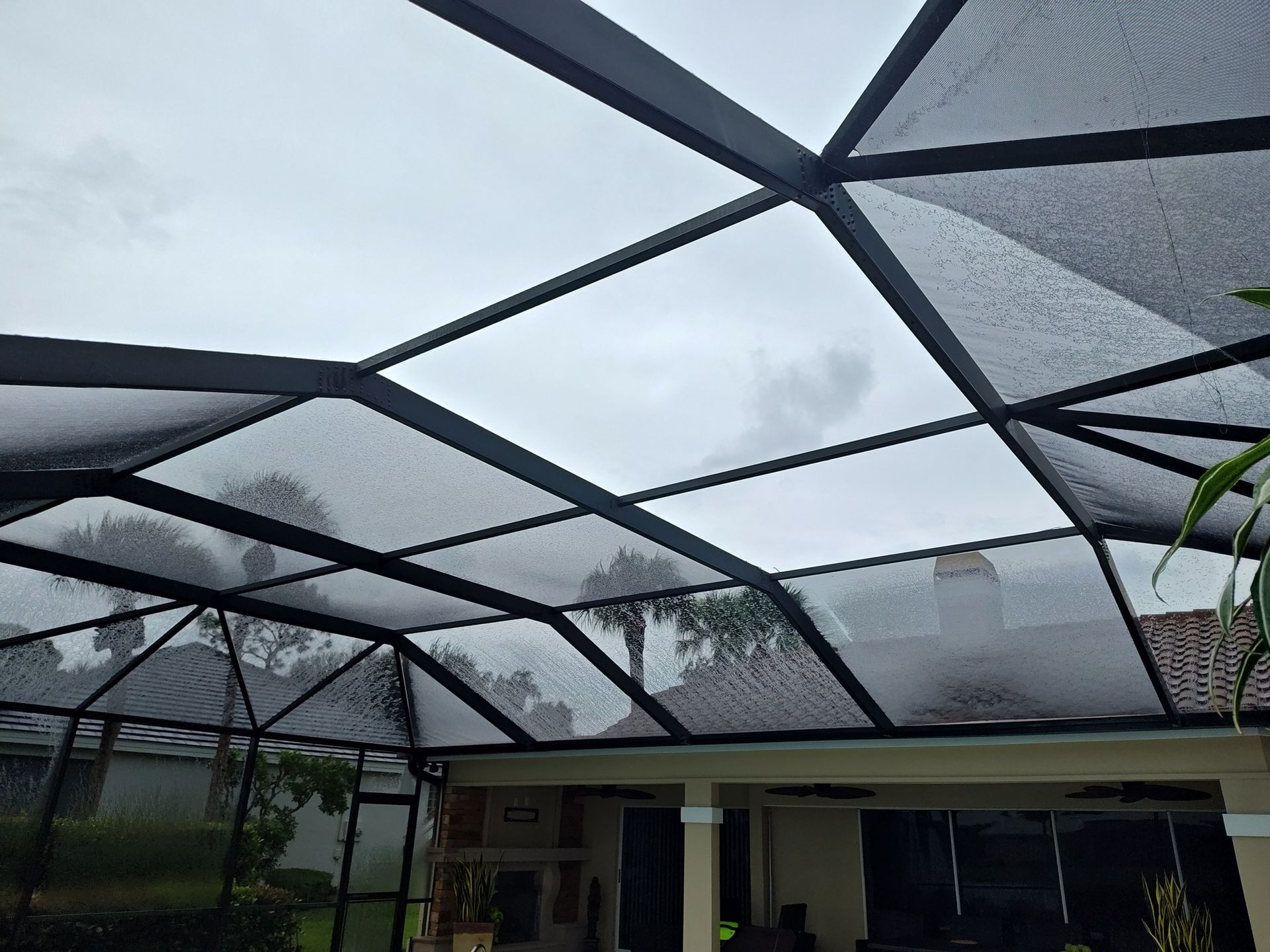 A screened in porch with a clear roof on a cloudy day.