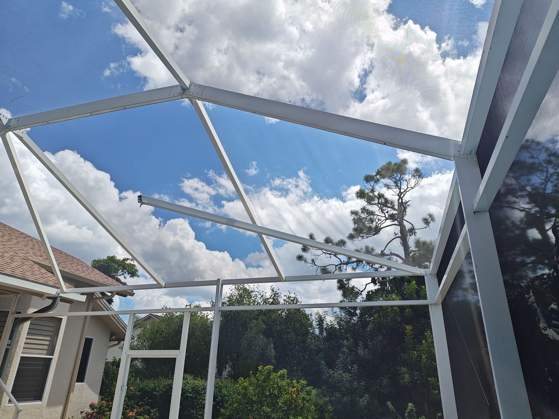 A screened in porch with a blue sky and clouds behind it.