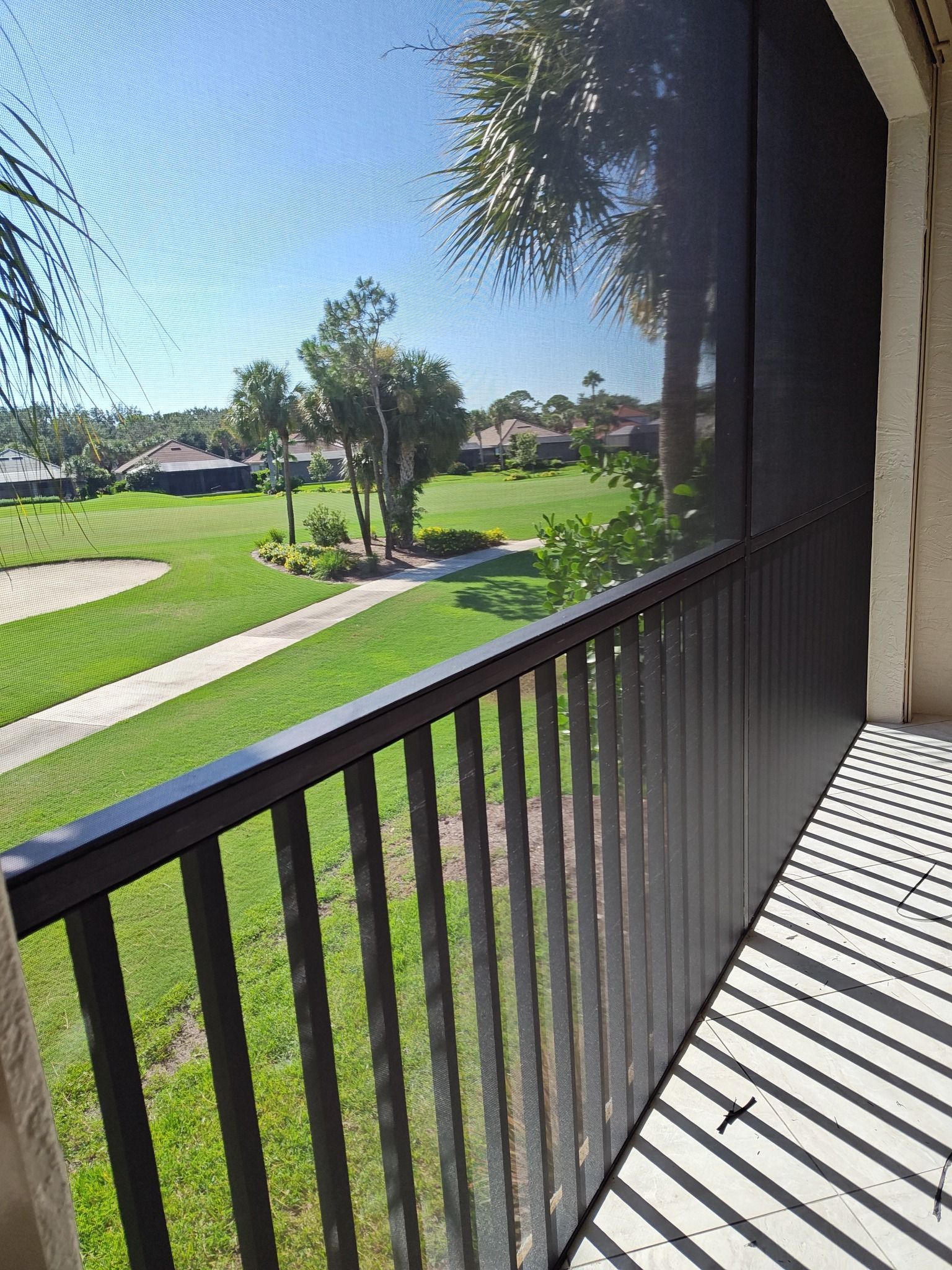 A balcony with a screened in view of a golf course.