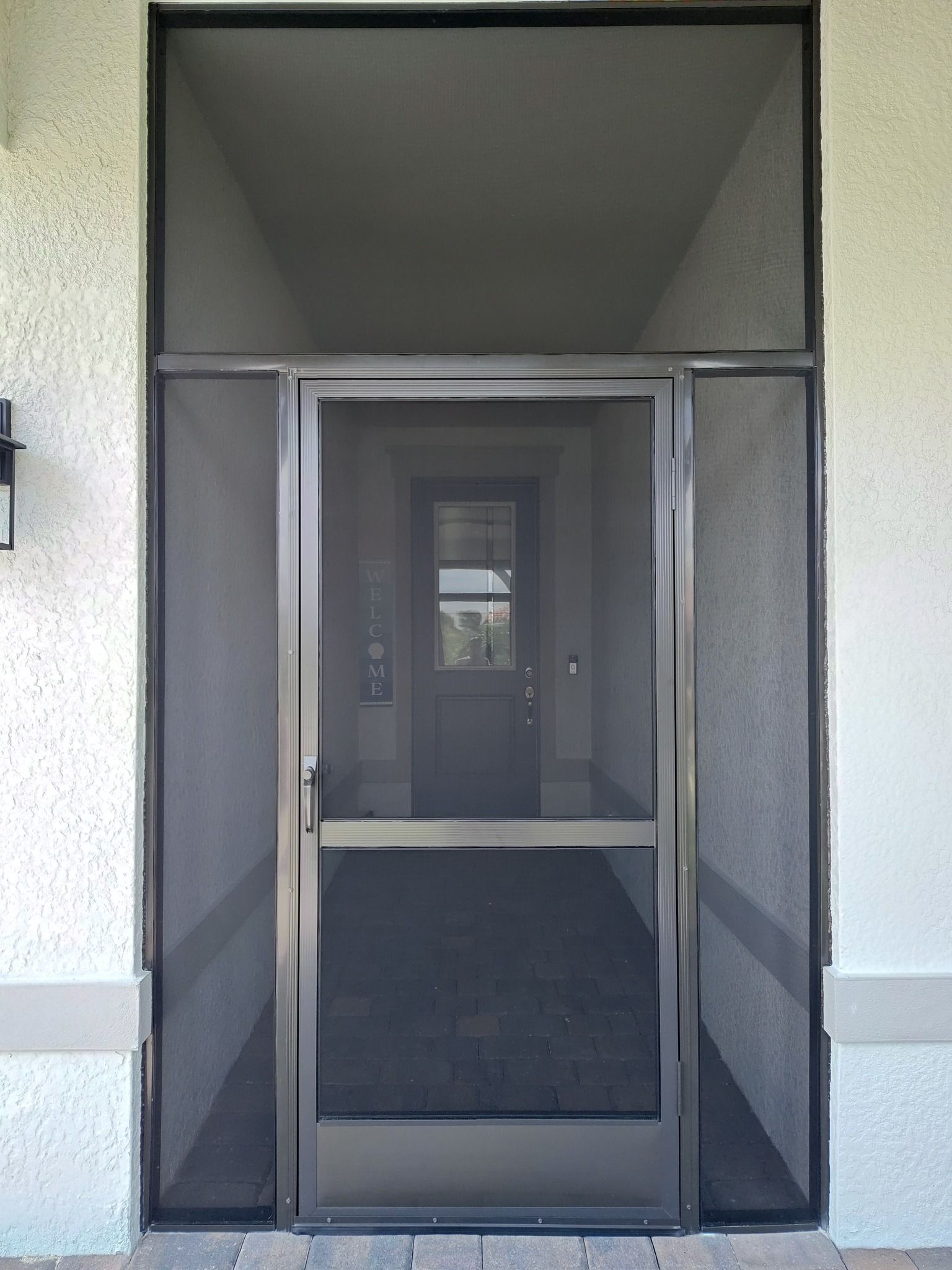 A screen door is open to a hallway leading to a door