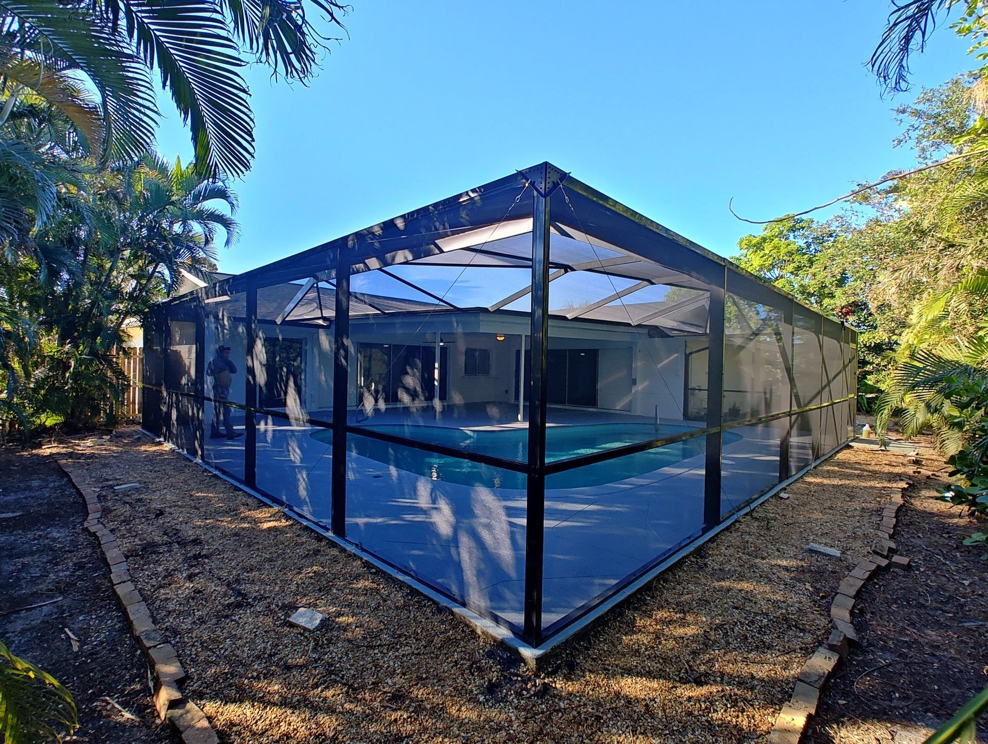 A swimming pool with a screened in area in front of it.