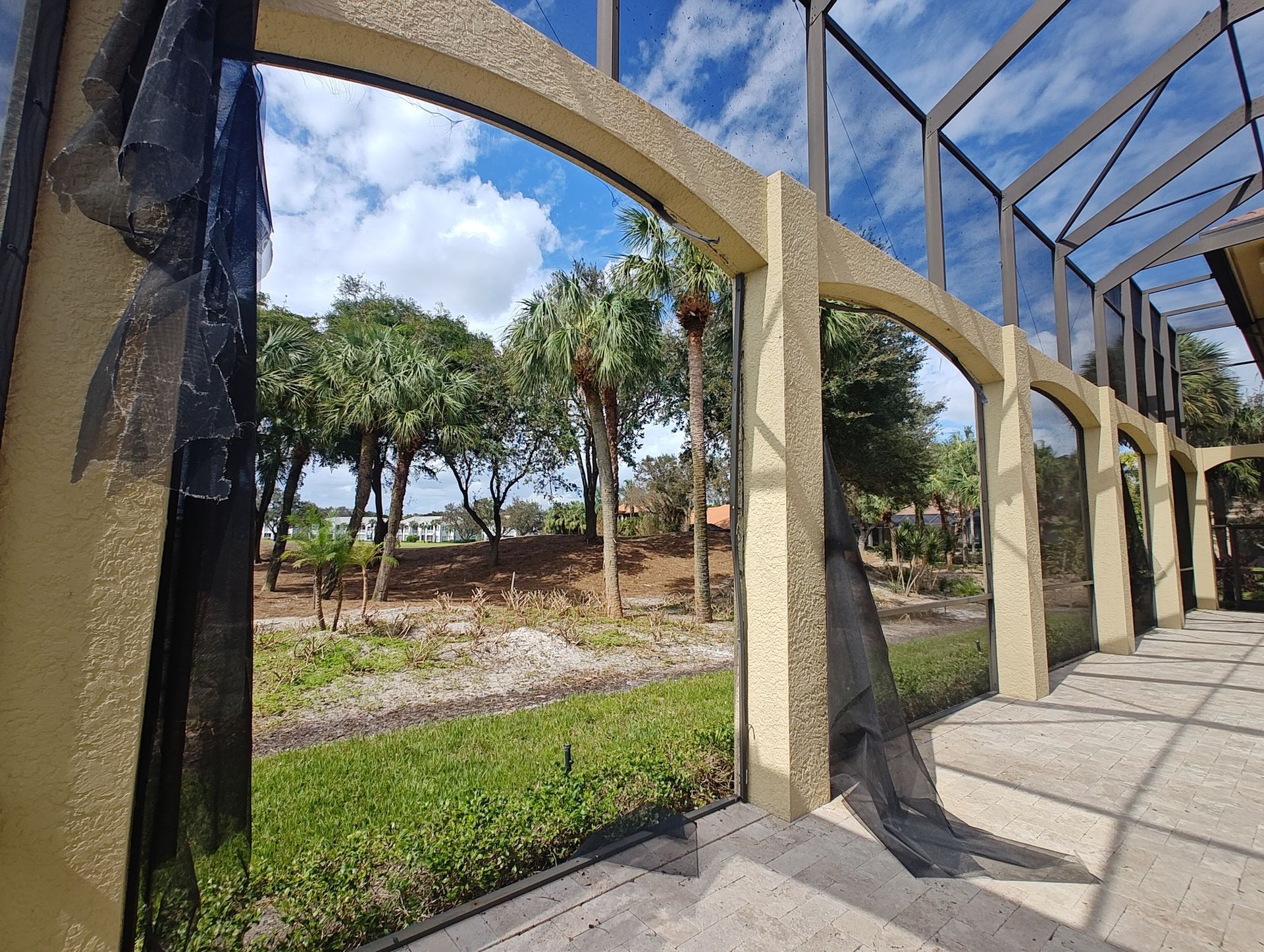 A view of a lush green park through a screened in area.