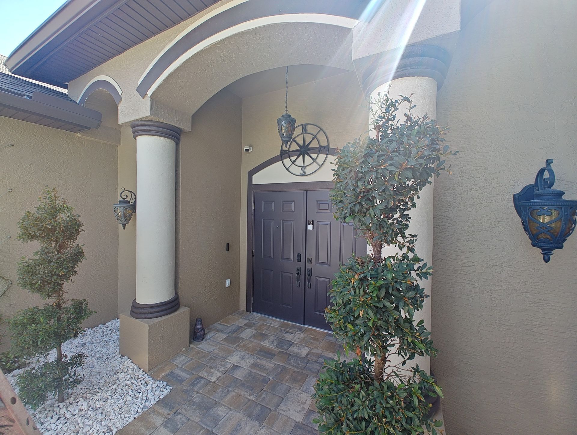 The front door of a house is surrounded by trees and rocks.