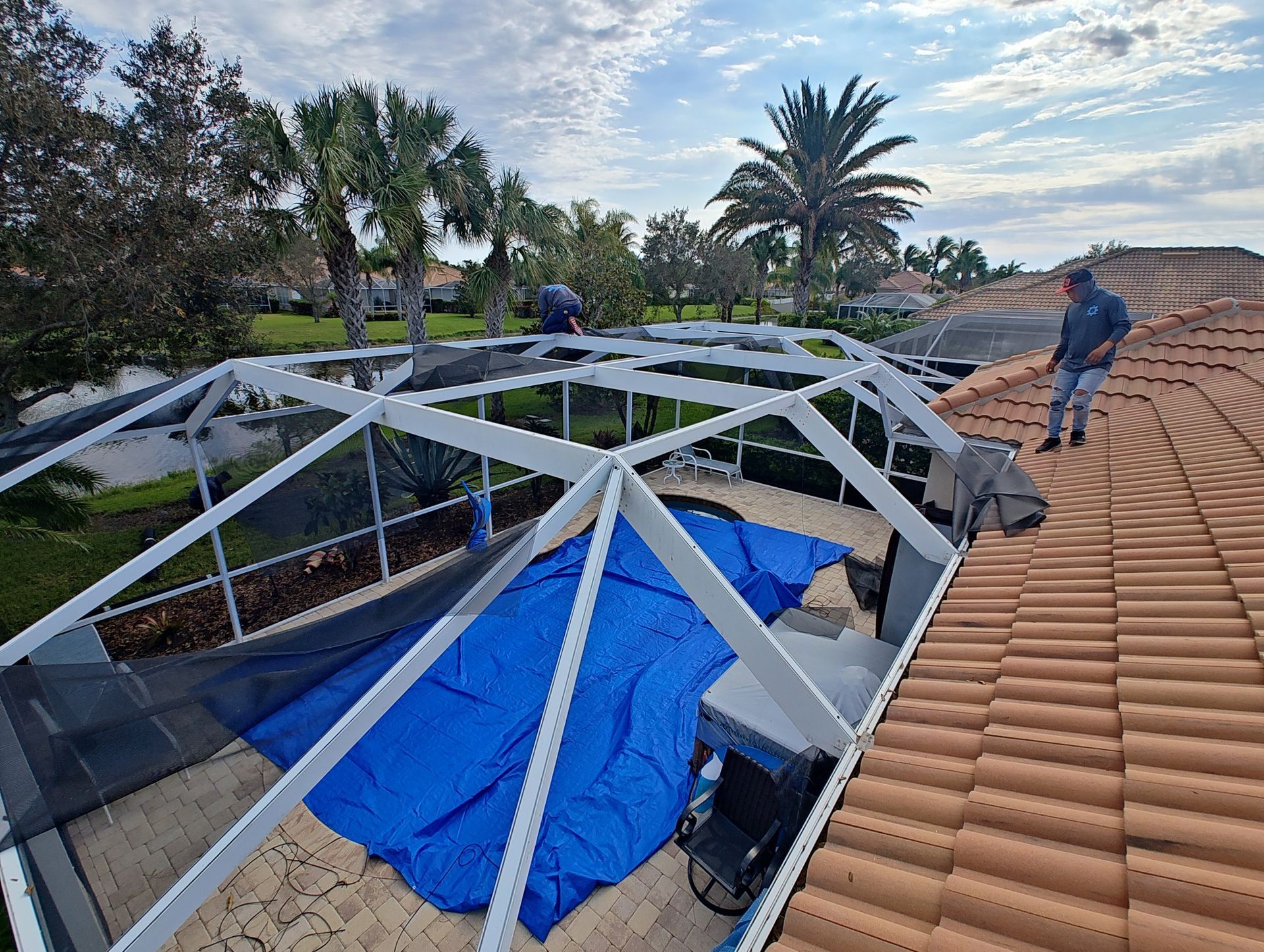 A man is standing on top of a roof next to a pool.