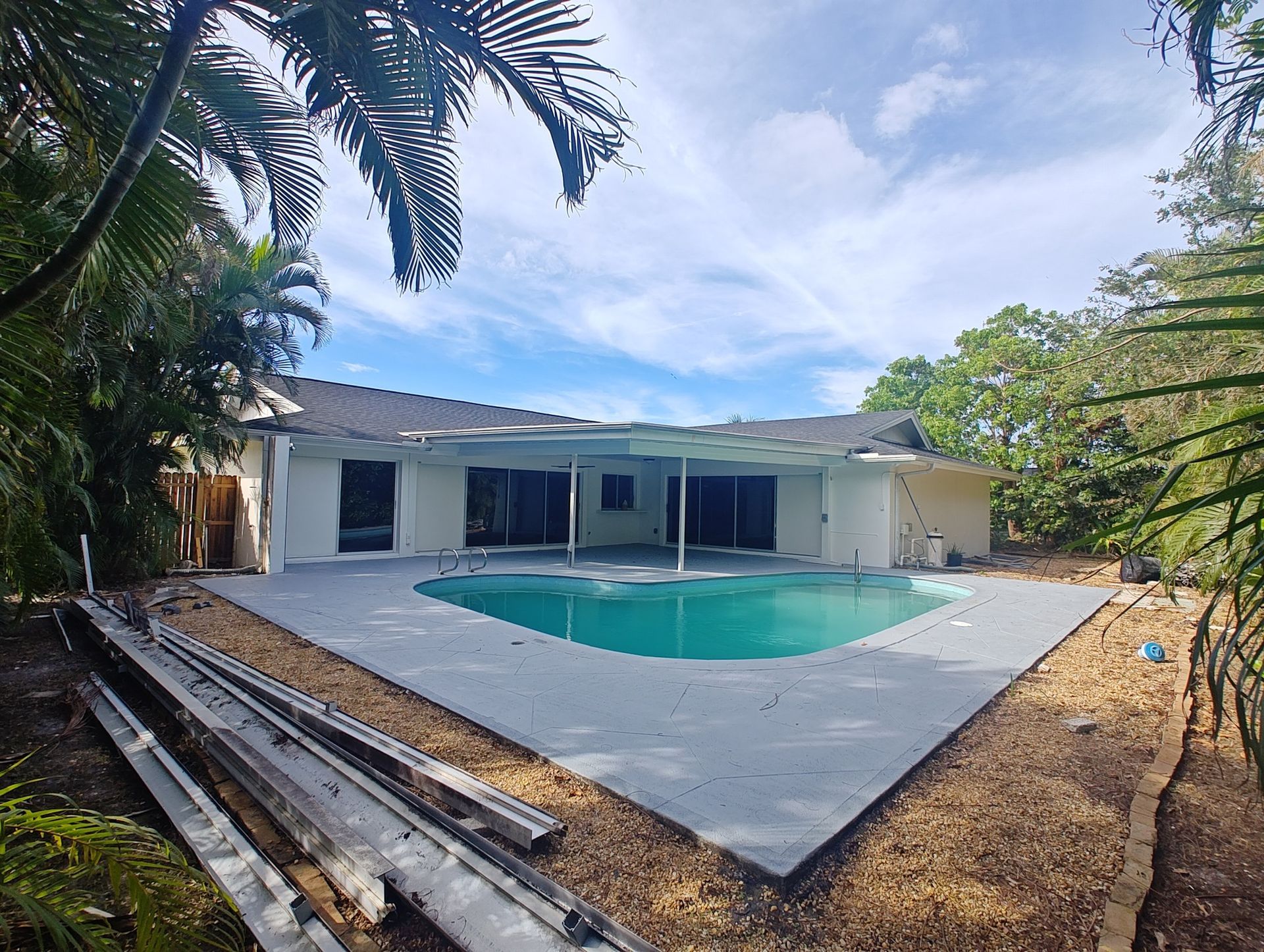 A large swimming pool is in the backyard of a house.