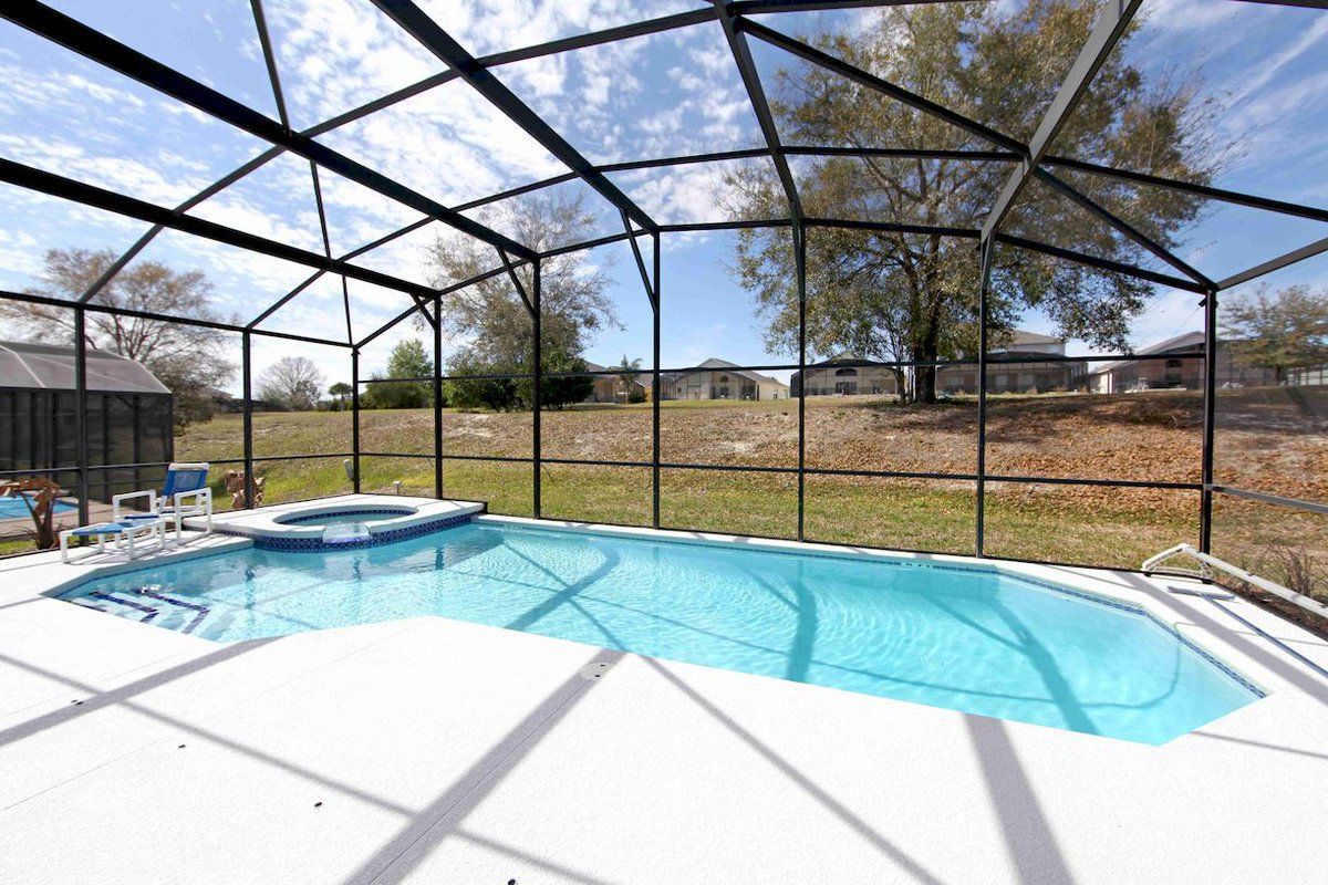 A large swimming pool with a screened in area in the backyard.