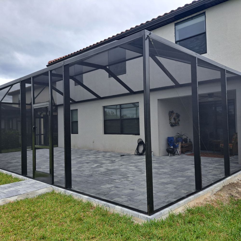 A screened in porch with a patio in front of a house.