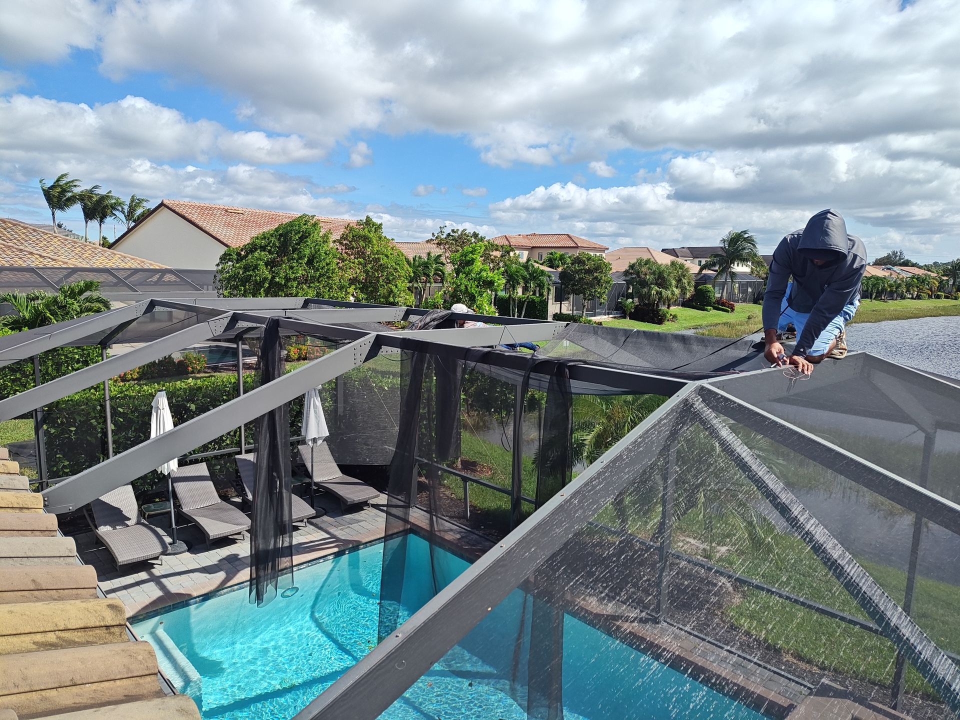 A man is working on a screened in swimming pool.