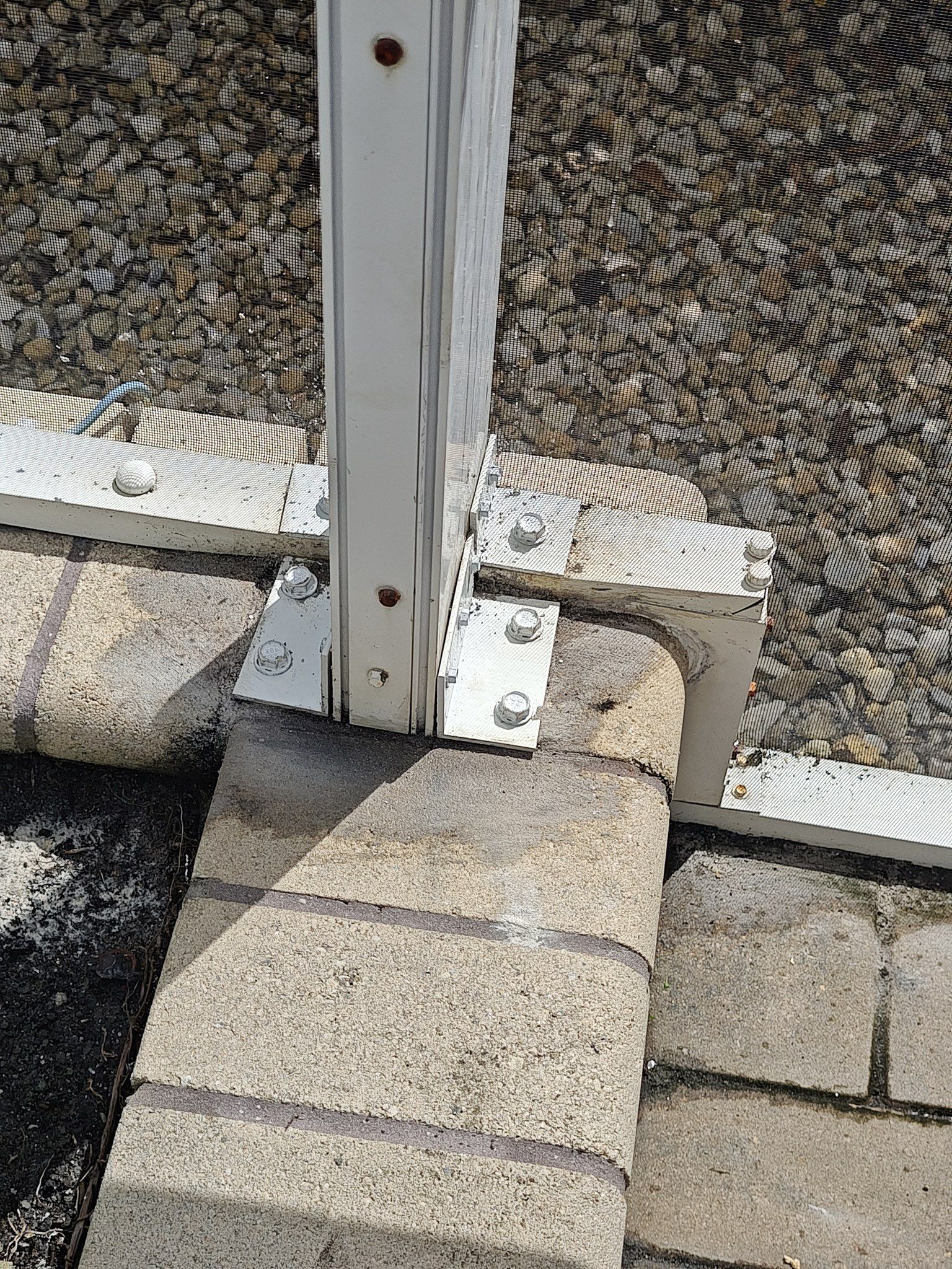 A white pole is sitting on top of a brick wall.