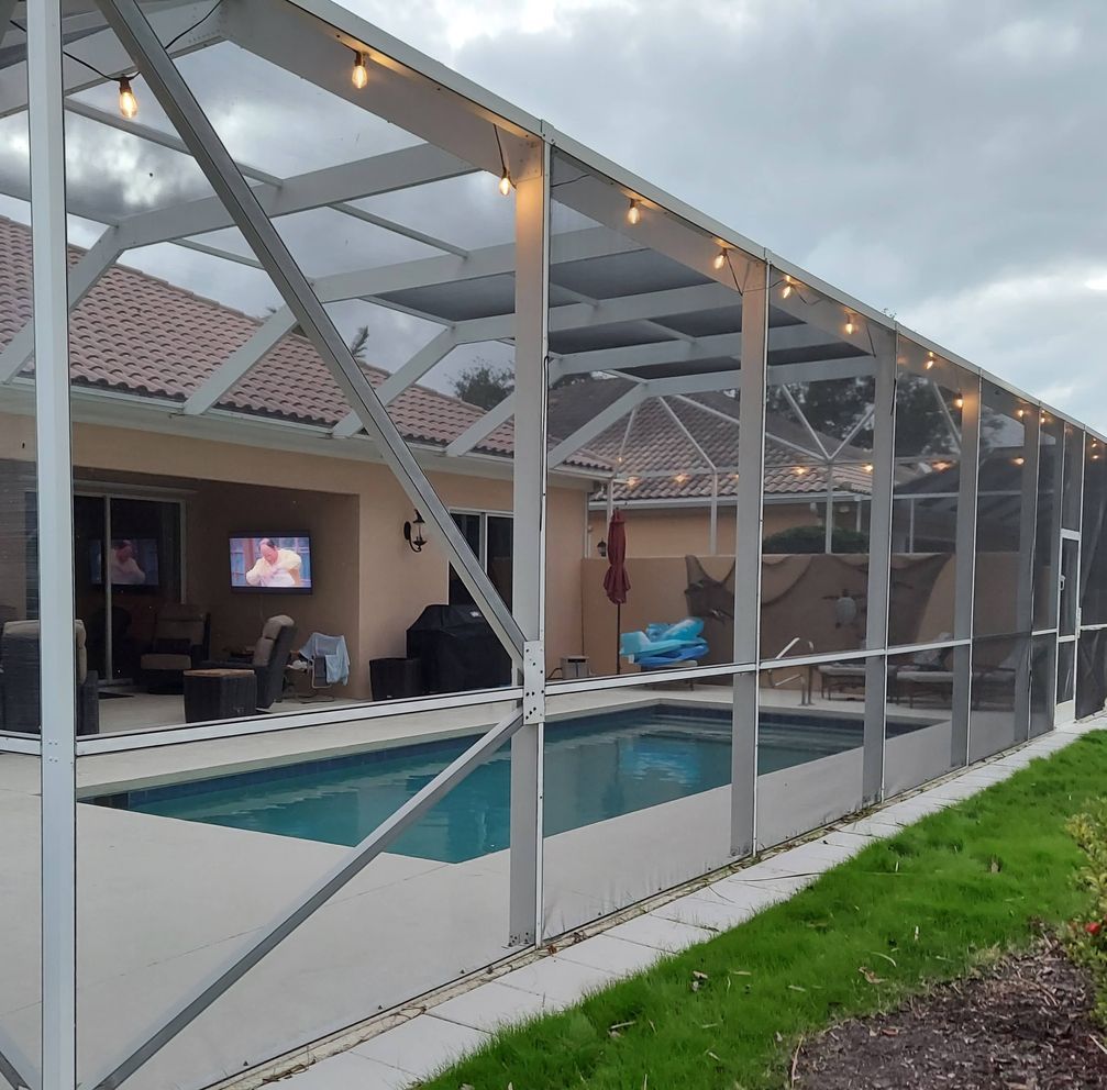 A screened in area with a swimming pool behind it