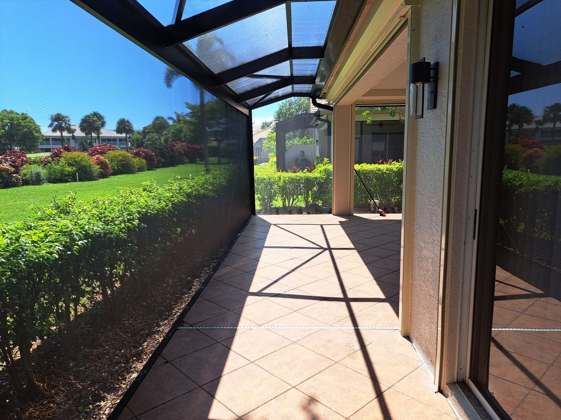 A screened in porch with a view of a lush green field