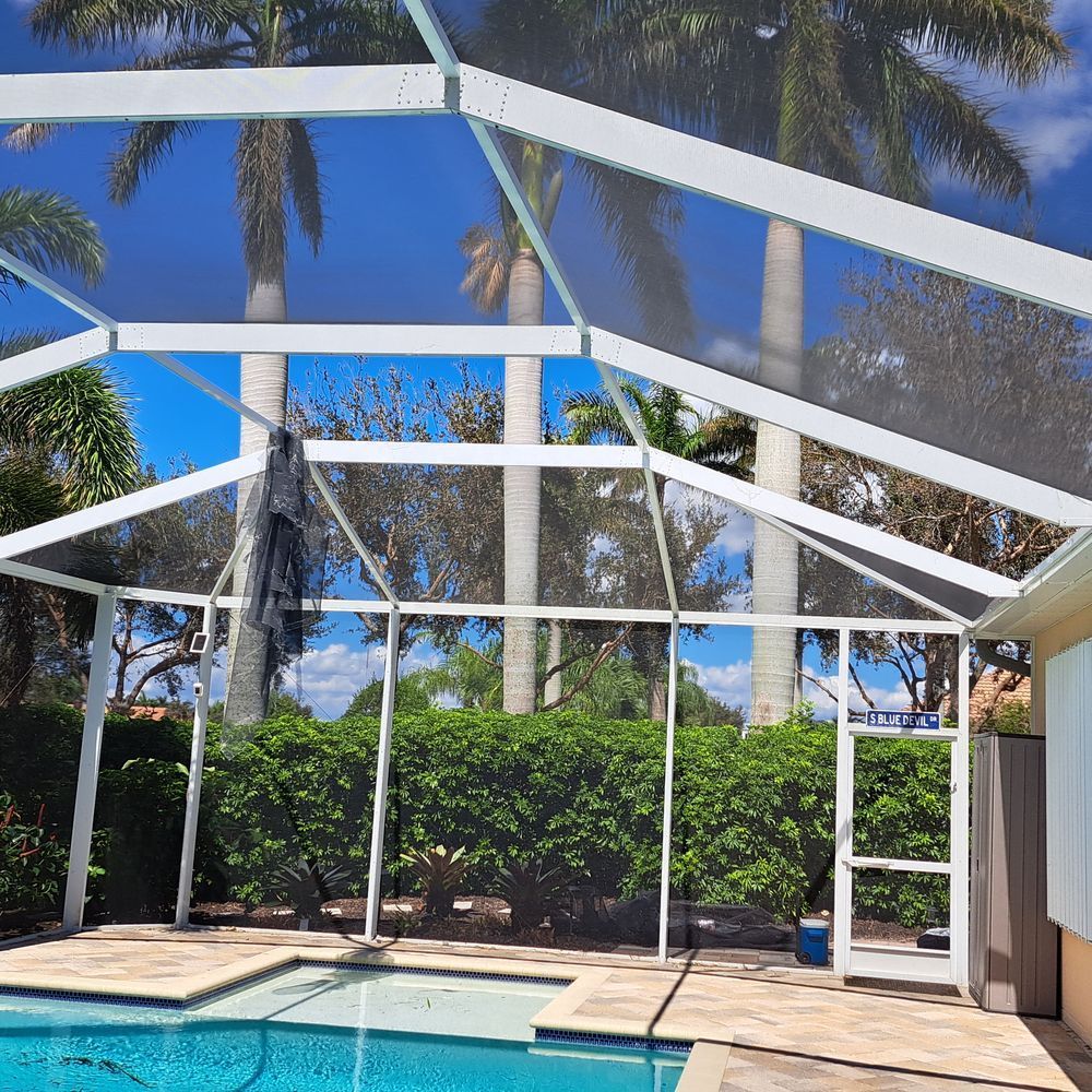 A screened in swimming pool with palm trees in the background