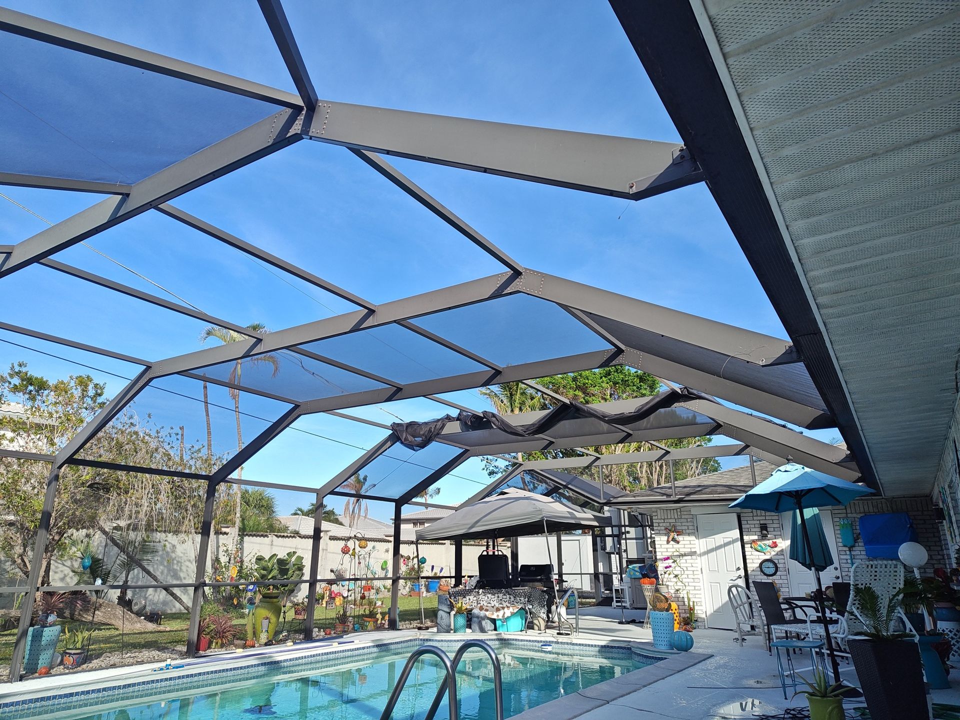 A swimming pool with a screened in area and a blue sky in the background.