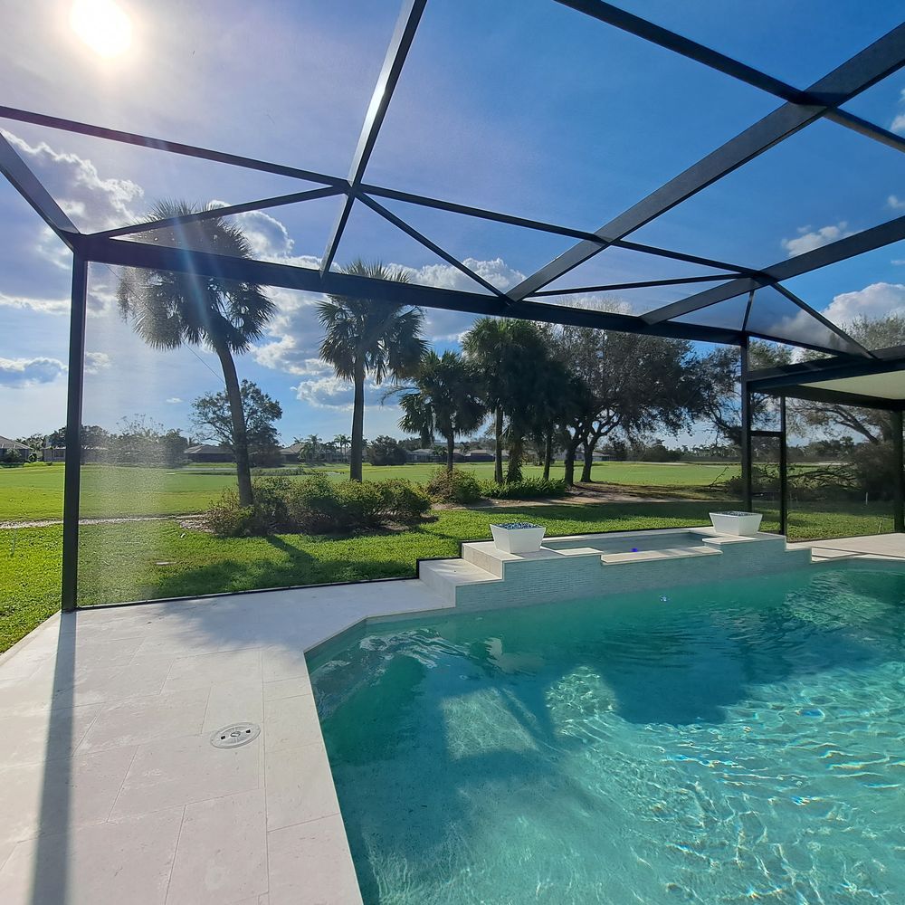 A swimming pool under a clear roof with palm trees in the background