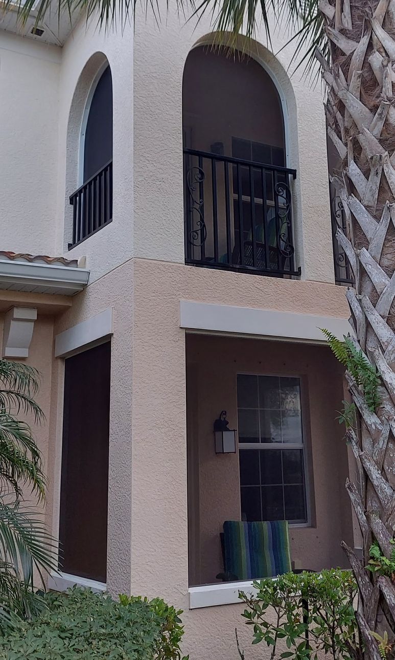A house with a balcony and a palm tree in the background.