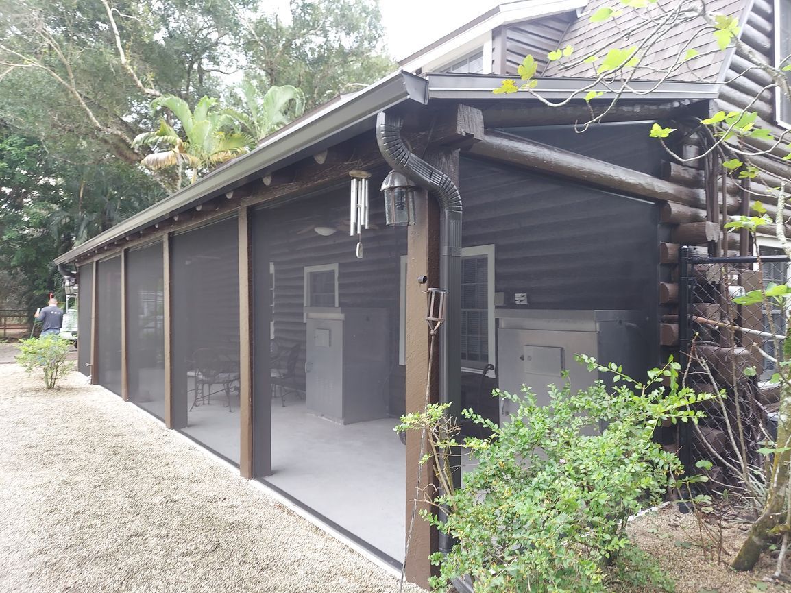 A screened in porch on the side of a house.
