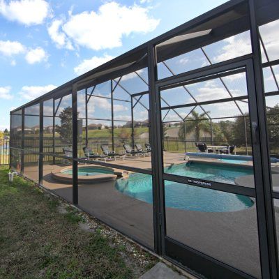 A screened in area with a swimming pool and chairs