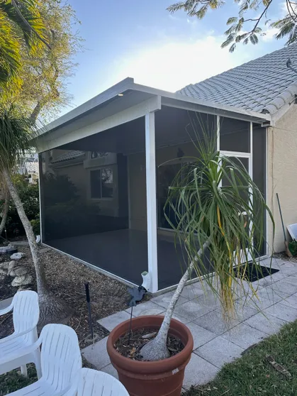 A screened in porch with a potted plant in front of it.
