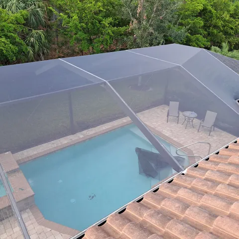 A screened in pool with chairs and tables under it
