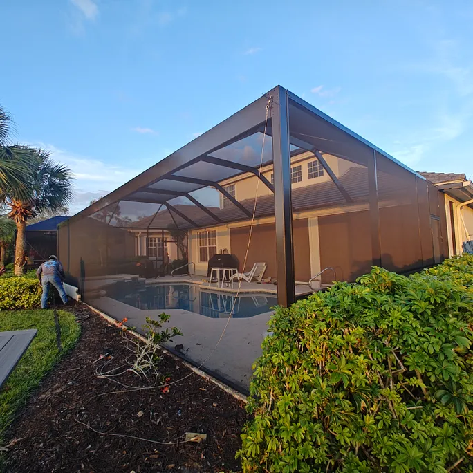 A screened in patio with a swimming pool in the background.