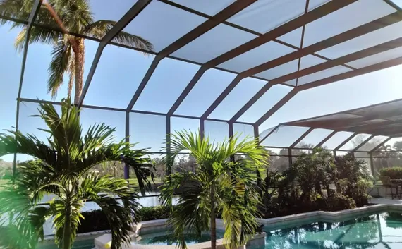 A screened in area with a swimming pool and palm trees