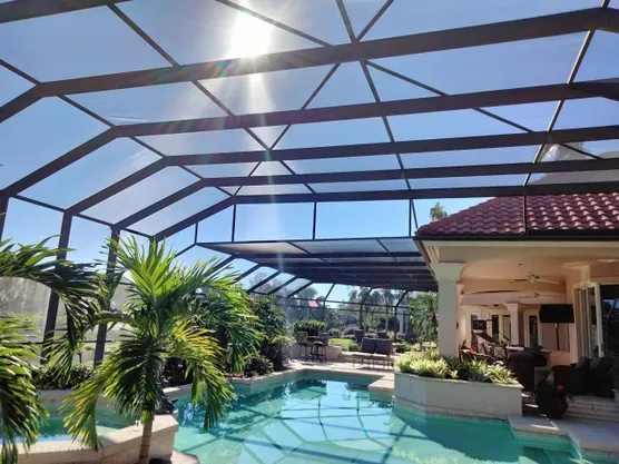 A large swimming pool is surrounded by a screened in area.