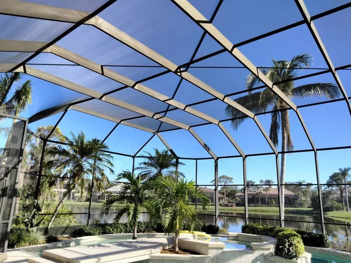 A screened in area with palm trees and a swimming pool