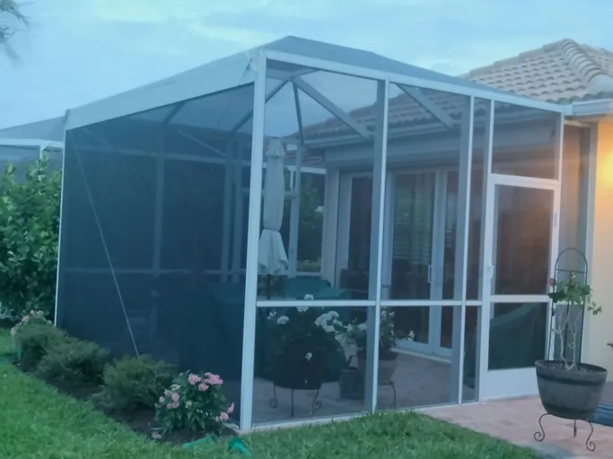 A screened in porch in the backyard of a house