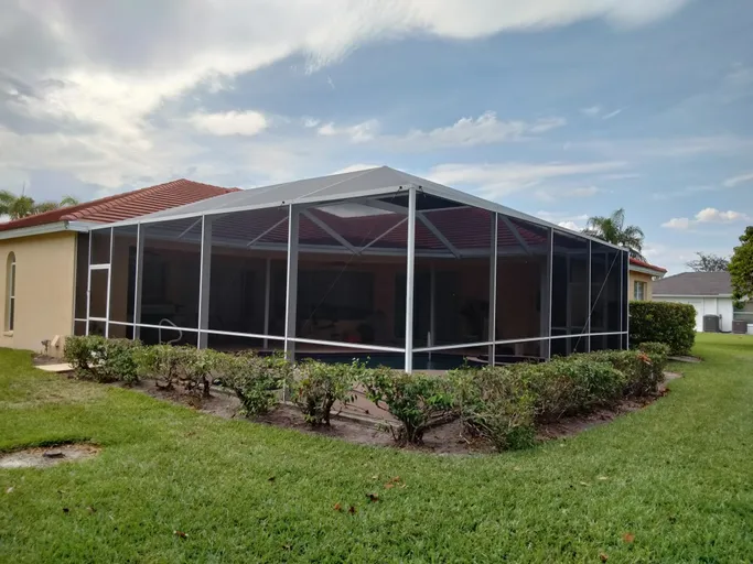 There is a screened in porch in the backyard of a house.