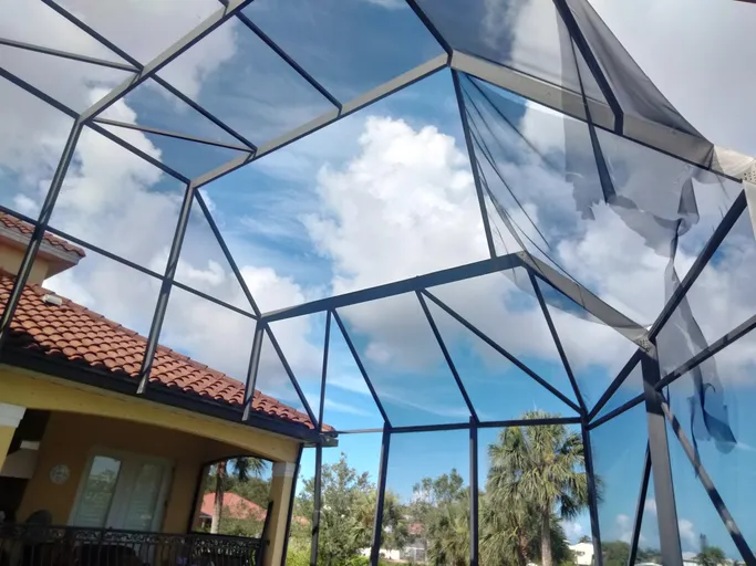 A screened in porch with a blue sky behind it