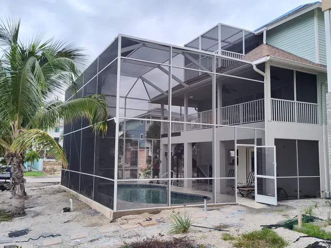 A large house with a screened in swimming pool in the backyard.