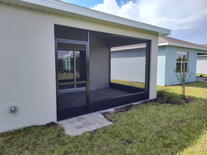 There is a screened in porch in the backyard of a house.