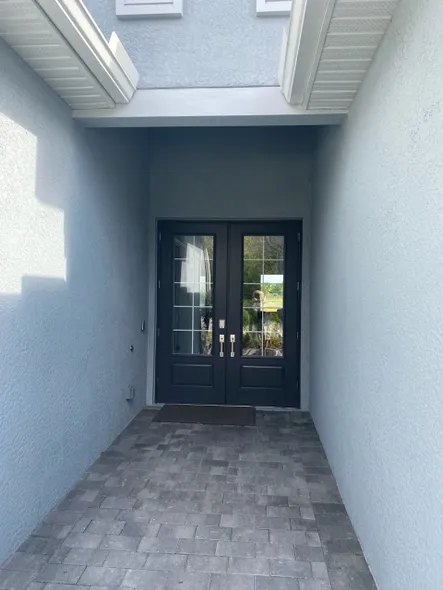 A brick walkway leading to a double door