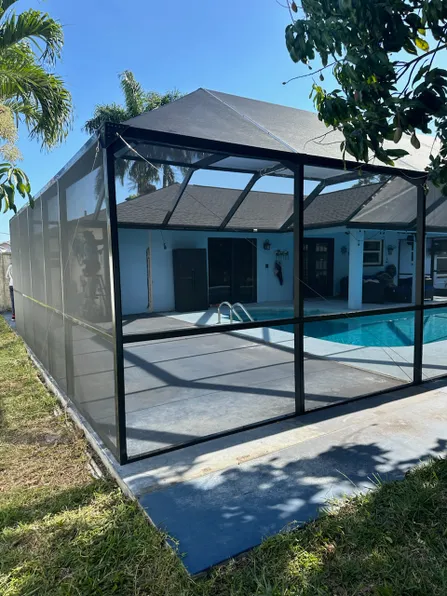 A screened in area with a swimming pool in the background