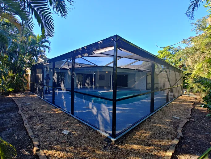 A screened in swimming pool in the backyard of a house