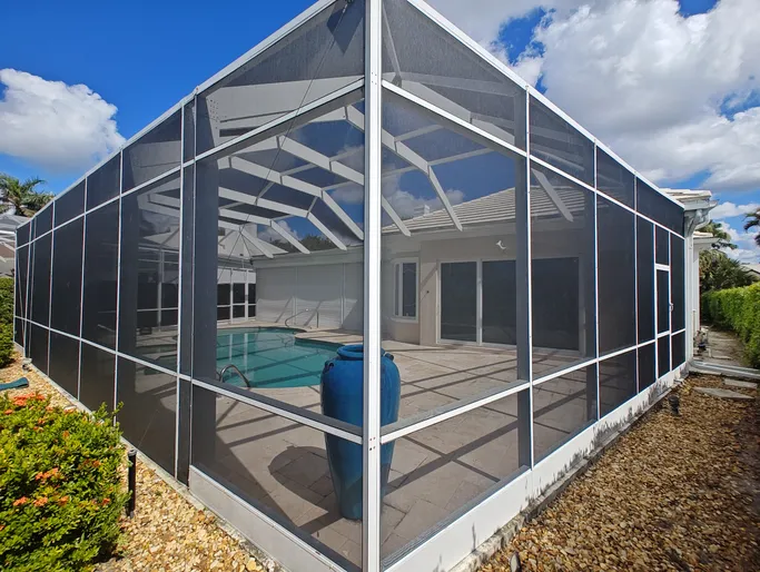 A screened in swimming pool with a blue vase in front of it