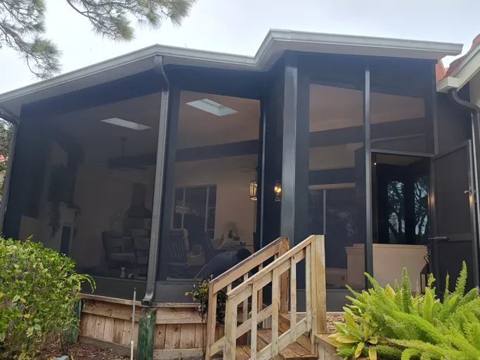 A house with a screened in porch and stairs leading to it.