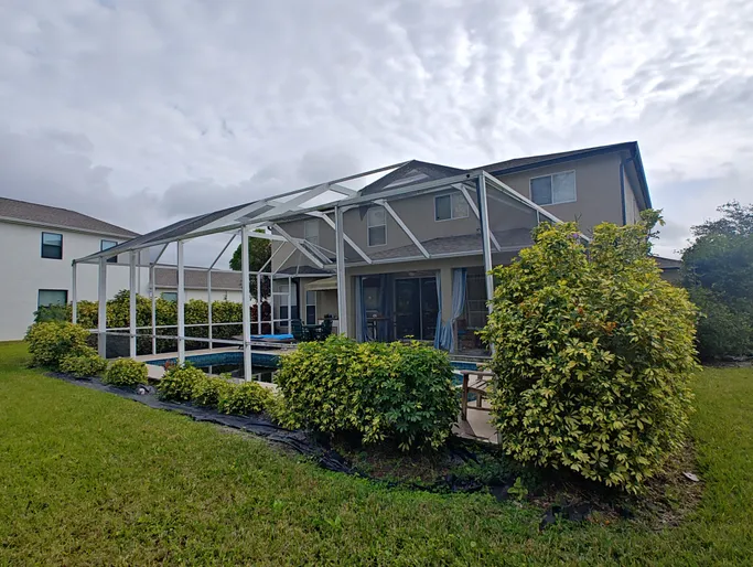 A house with a screened in porch and a pool in the backyard.