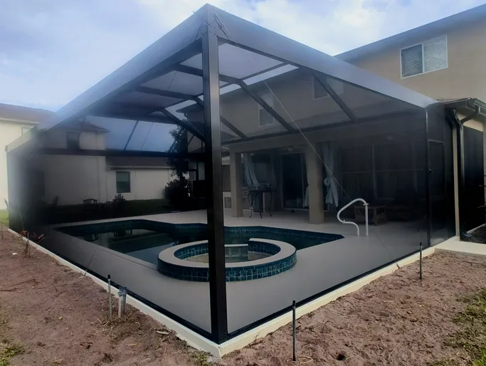 A screened in patio with a swimming pool and hot tub.