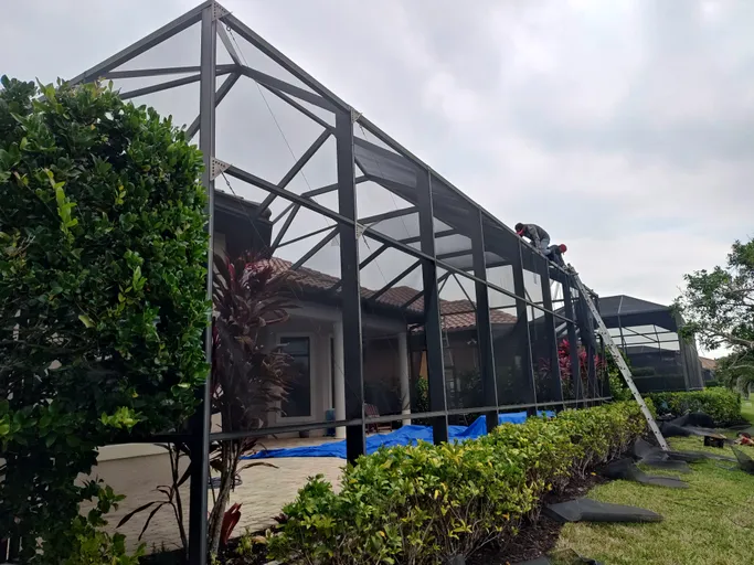 A screened in pool area is being built in the backyard of a house.