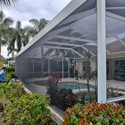 A screened in porch with a swimming pool in the background.